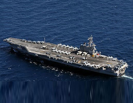 A large aircraft carrier in the ocean with other boats.